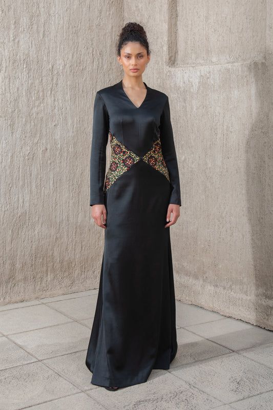 Model in black evening gown with embroidered waist and structured cape