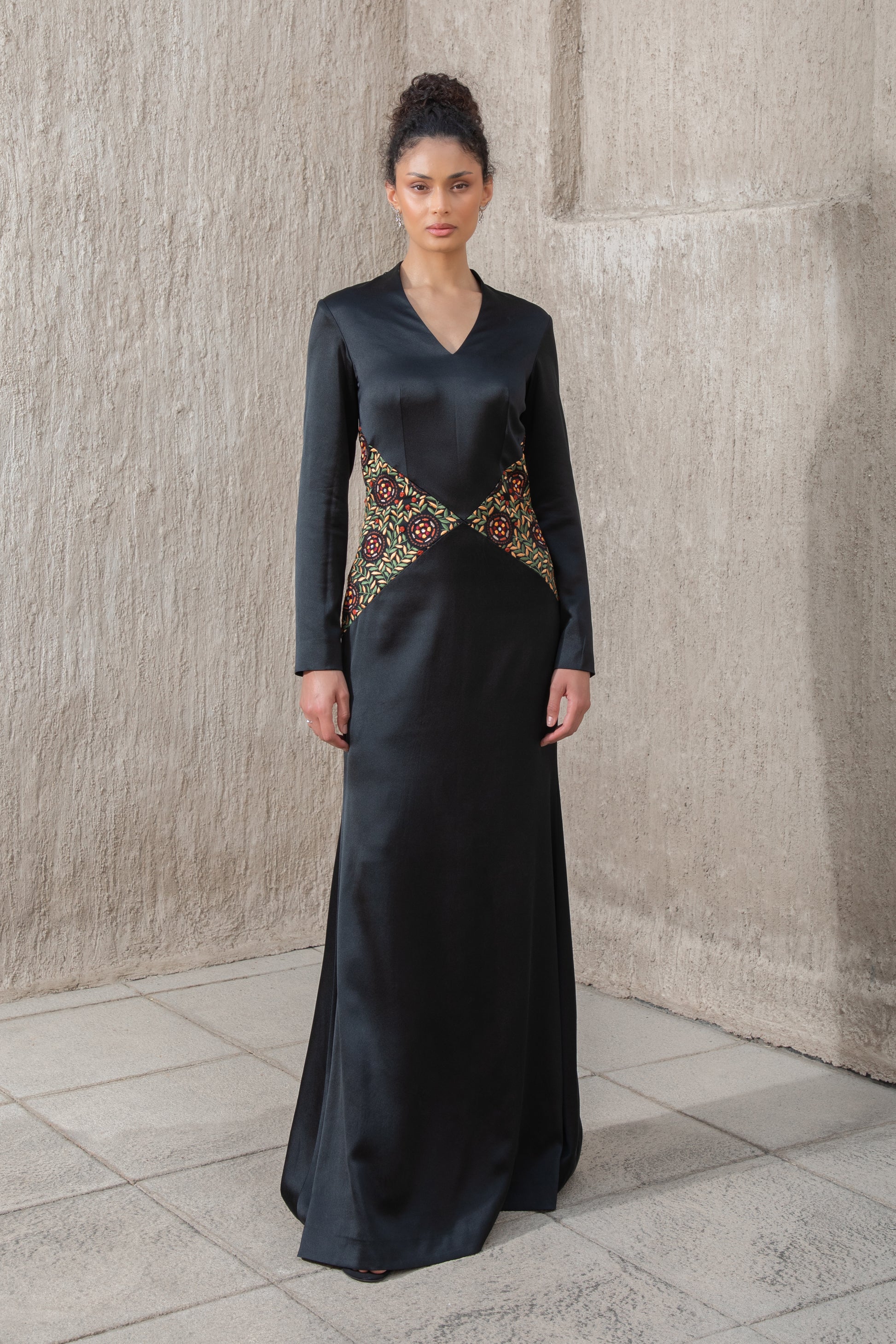 Model in black evening gown with embroidered waist and structured cape