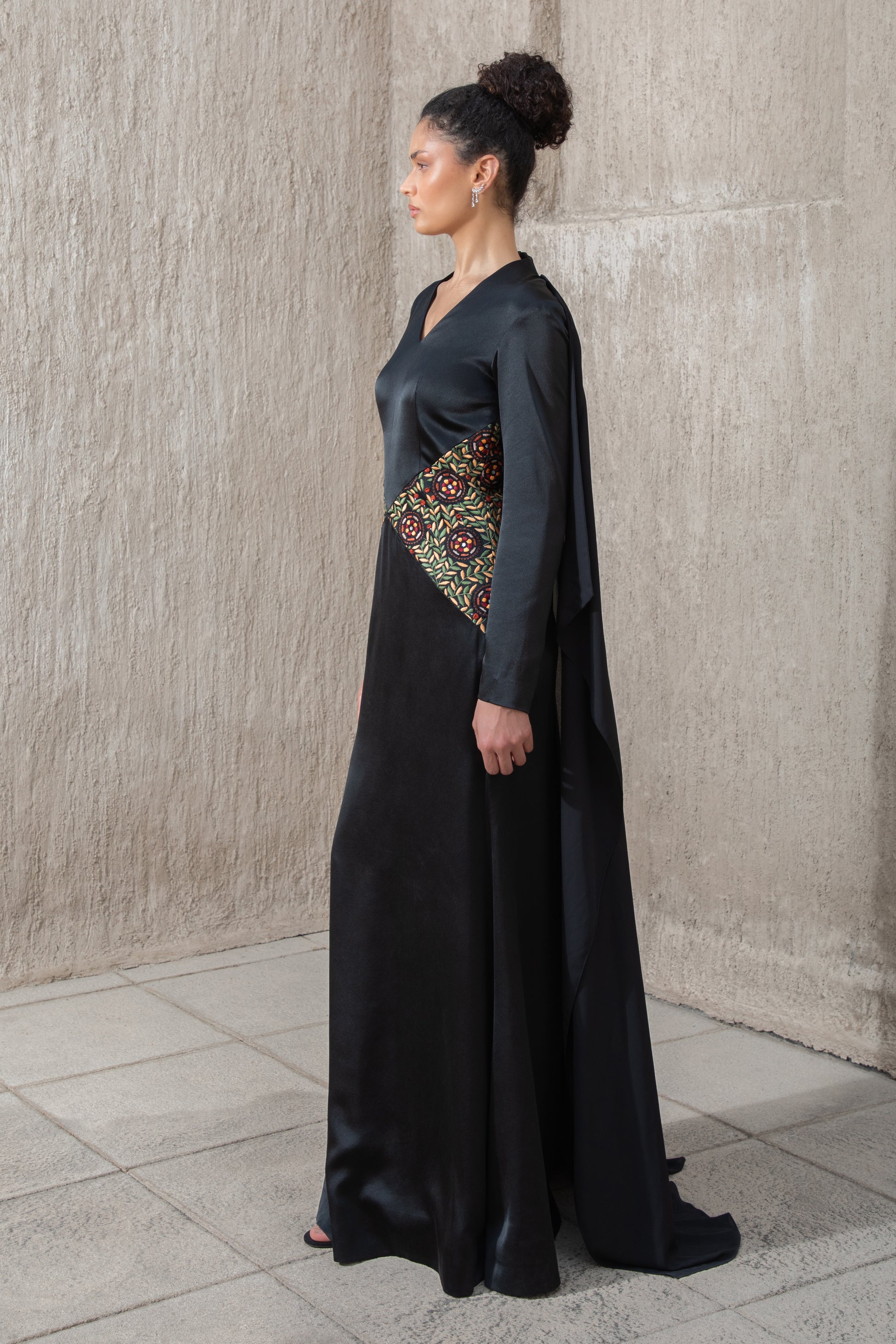 Side view of black gown with cape and colorful waist embroidery