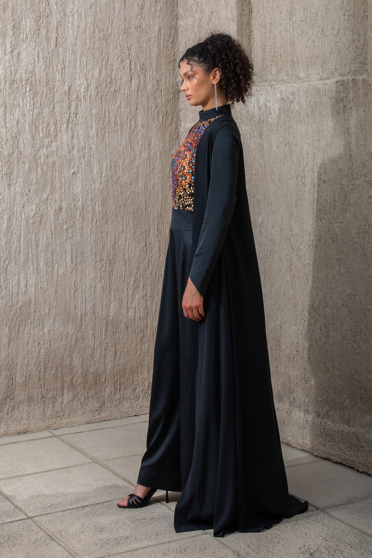 Side profile of black ice jumpsuit featuring flowing cape detail