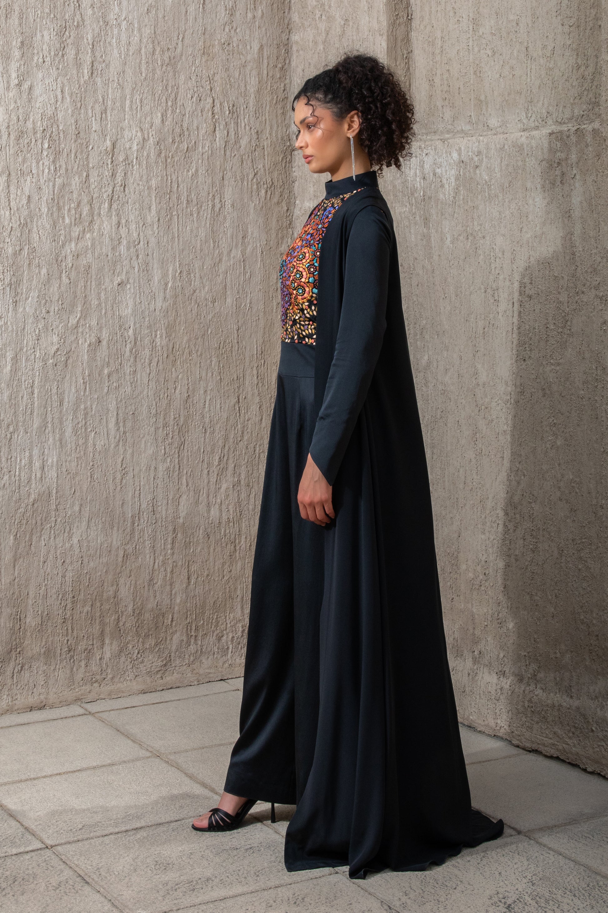 Side profile of black ice jumpsuit featuring flowing cape detail