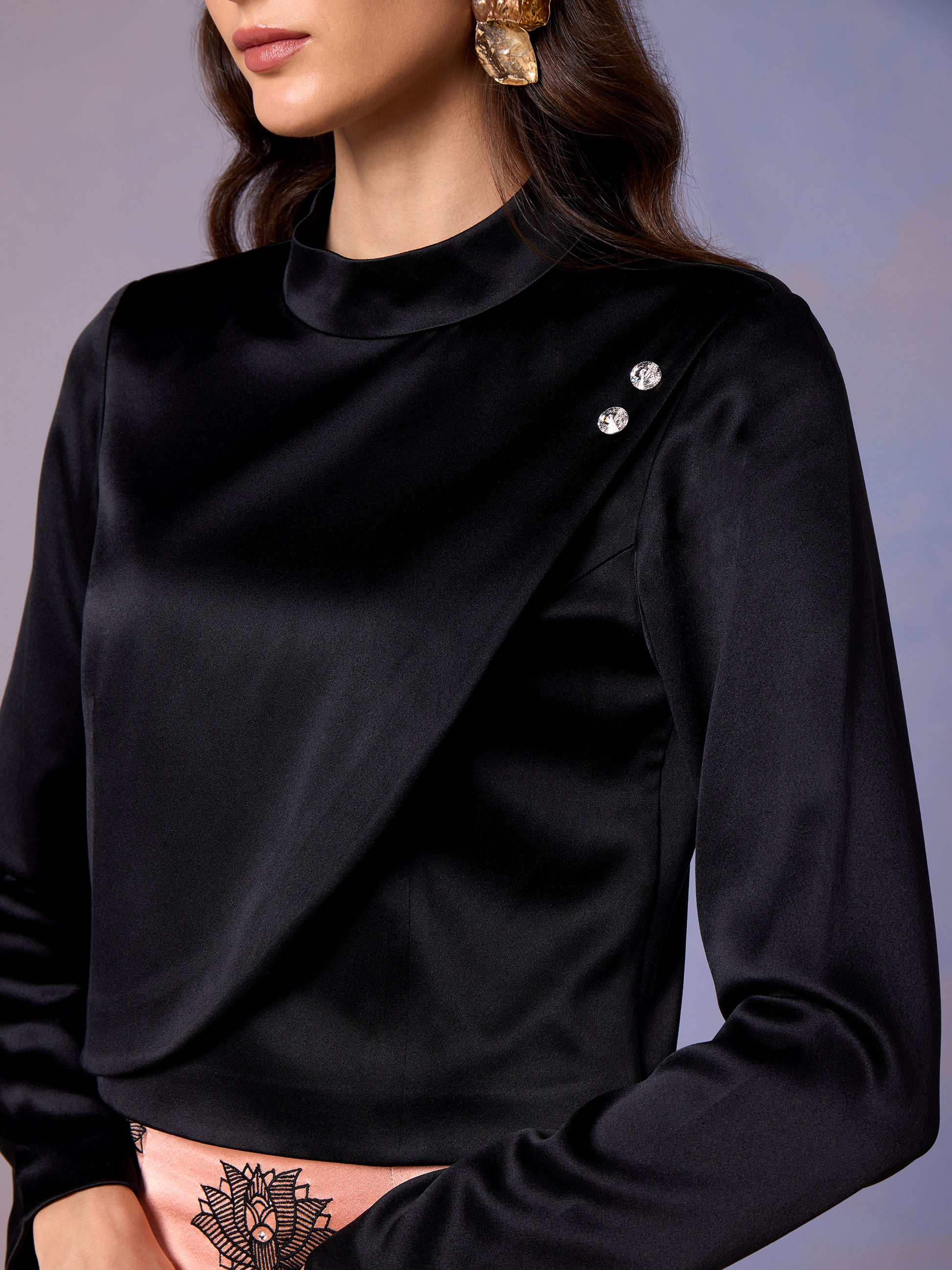 Detail of black satin top with button accents on shoulder
