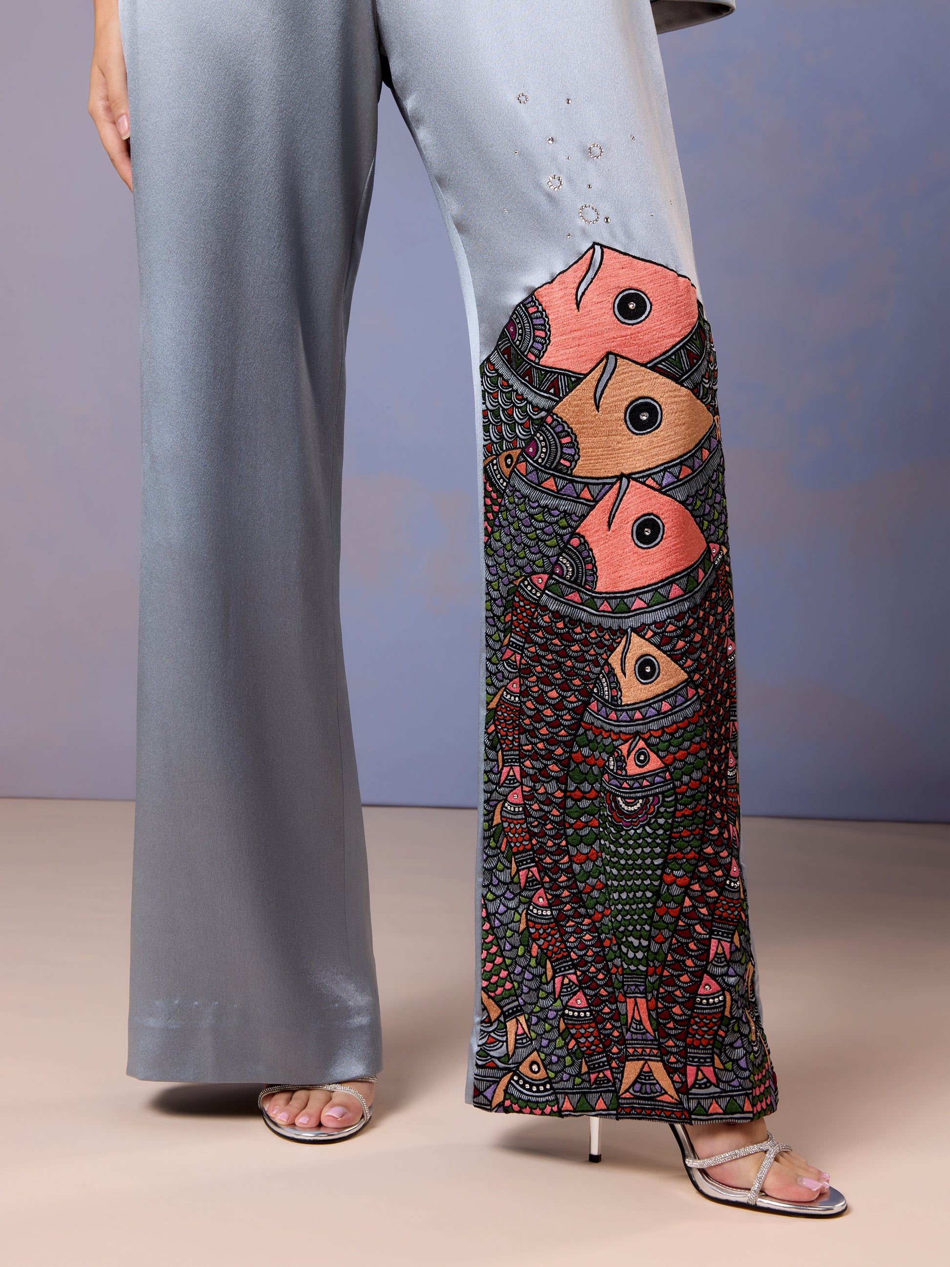 Close-up of floral embroidery on leg of glacier blue silk jumpsuit