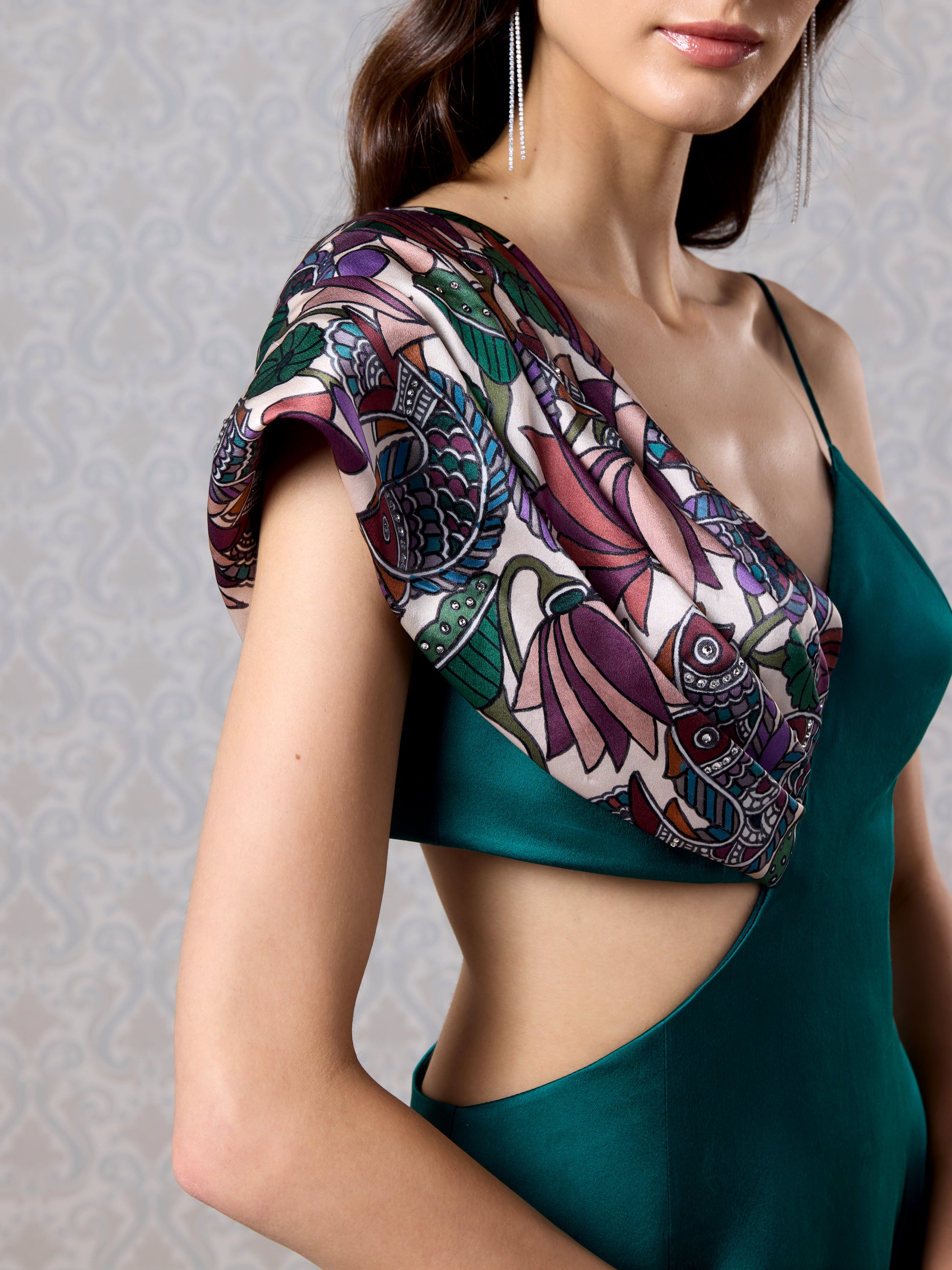 Close-up of printed shoulder drape and side cut-out on emerald silk satin gown