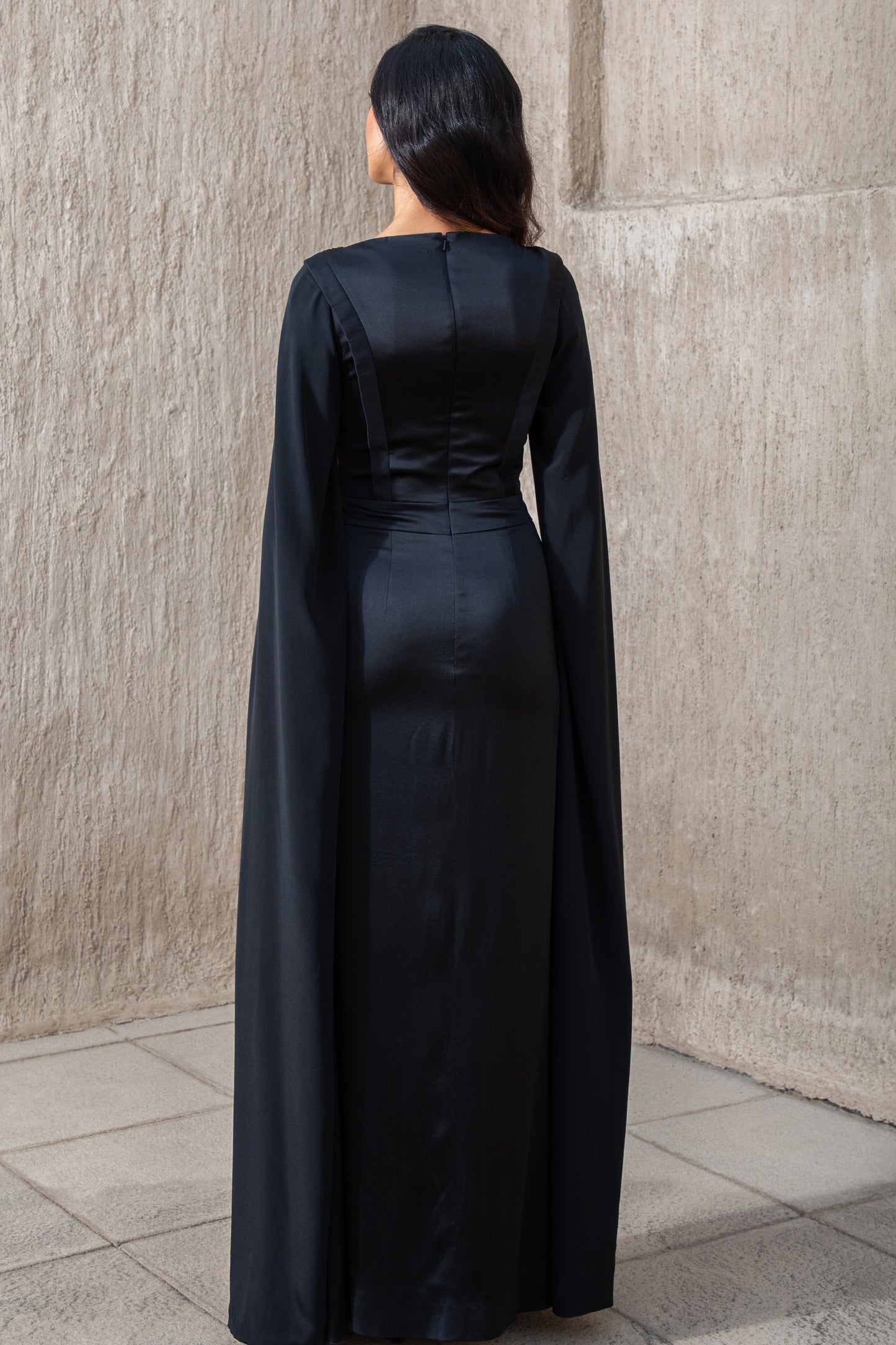 Back view of black evening gown with flowing cape sleeves