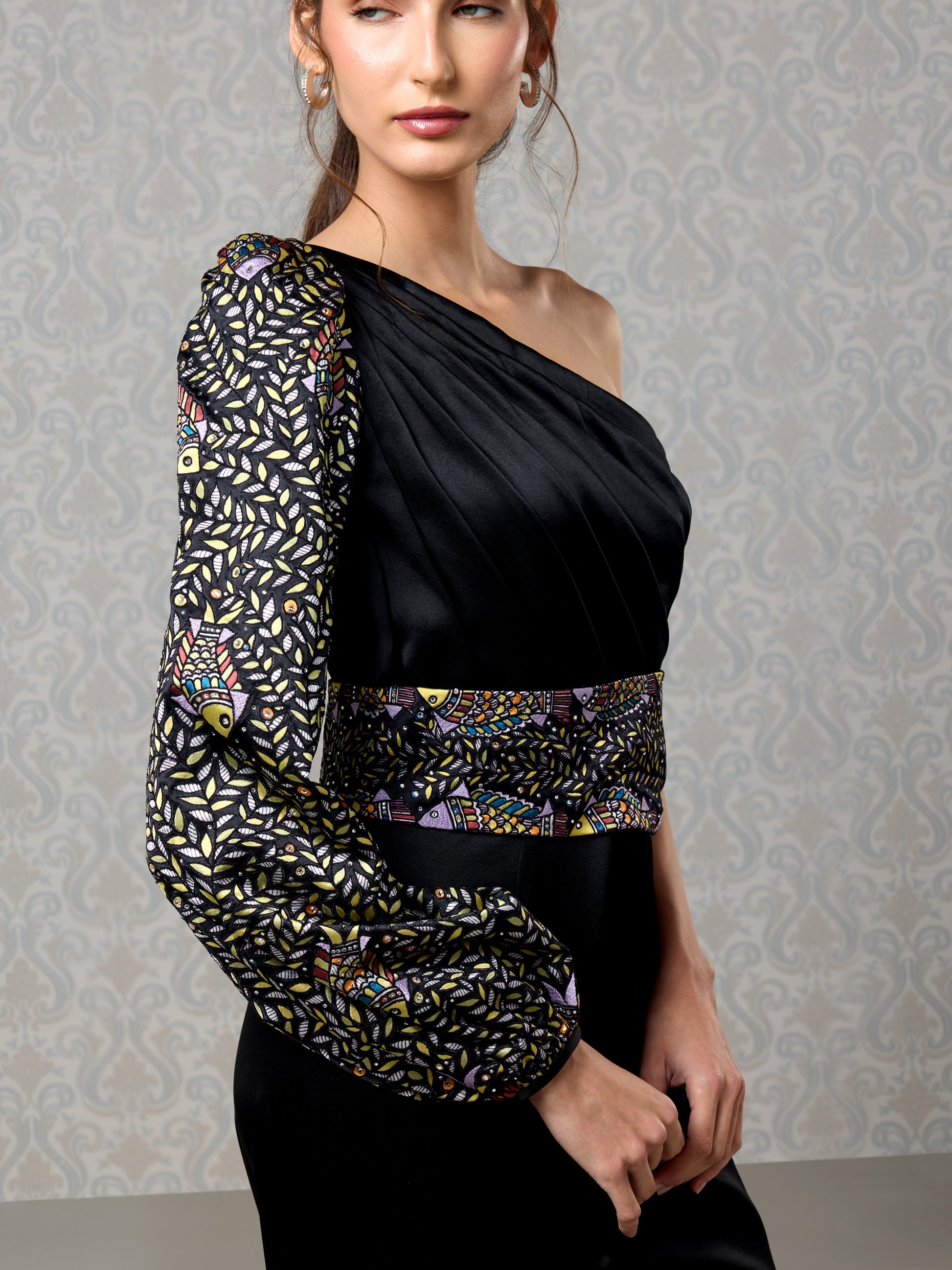 Close-up of black satin jumpsuit with intricate sequin work on shoulder and waist