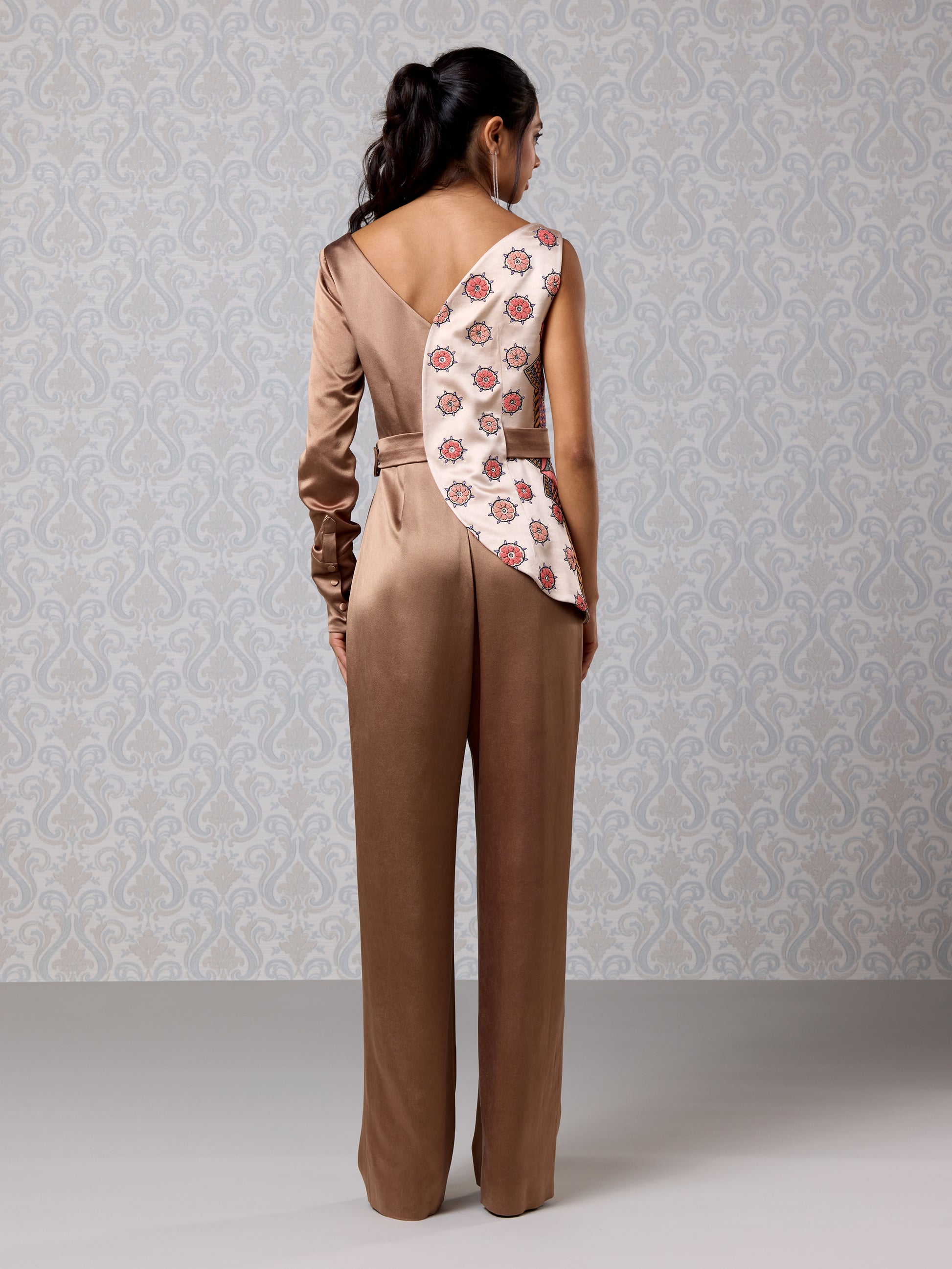 Back view of vanilla and brown jumpsuit with intricate embroidery and draped silhouette