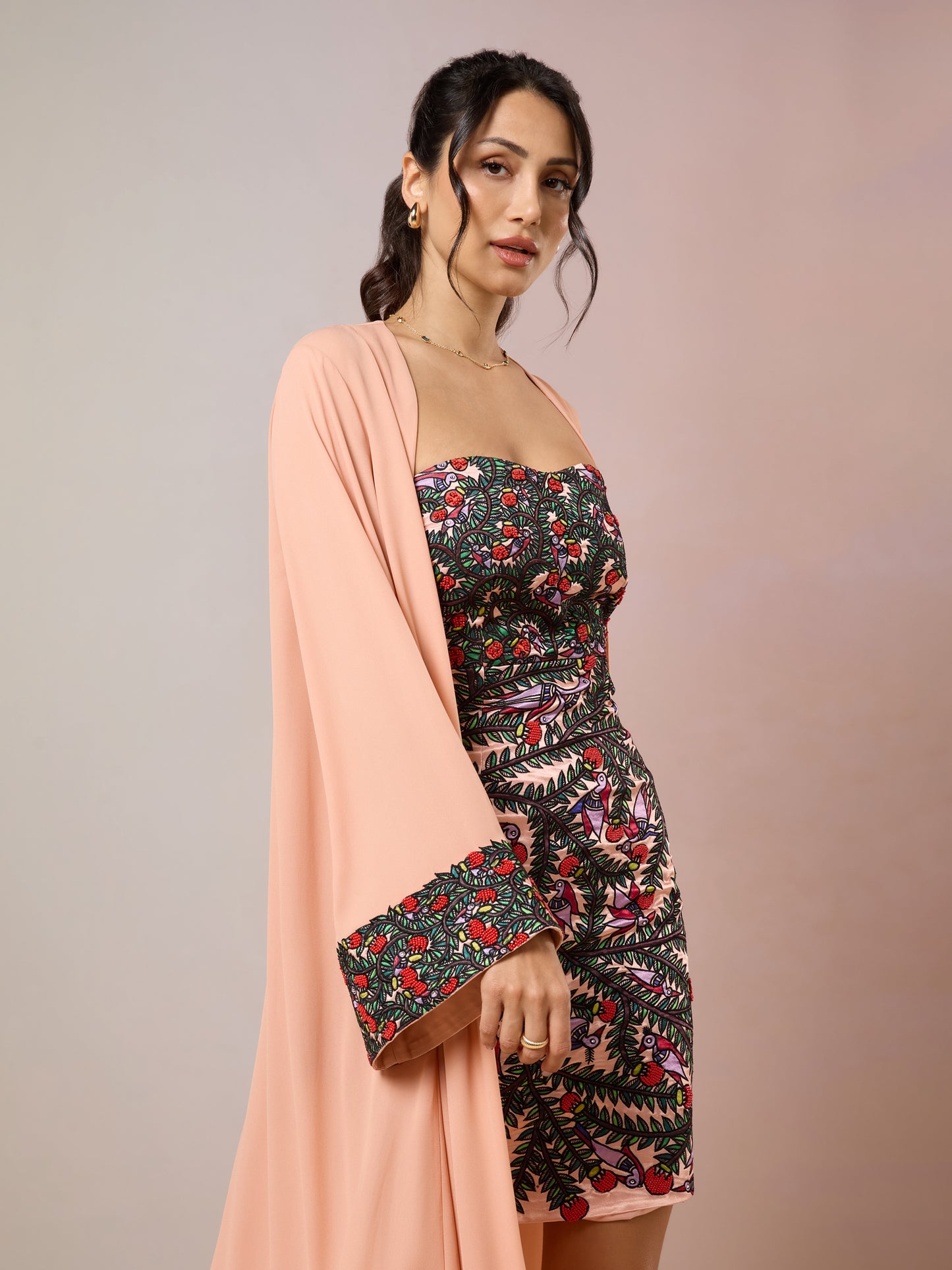 Side pose of floral mini dress with peach long cape jacket