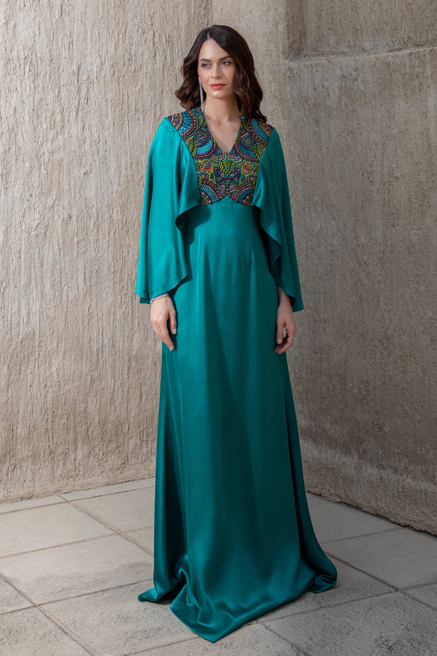 Model in emerald evening gown with embroidered neckline and long sleeves