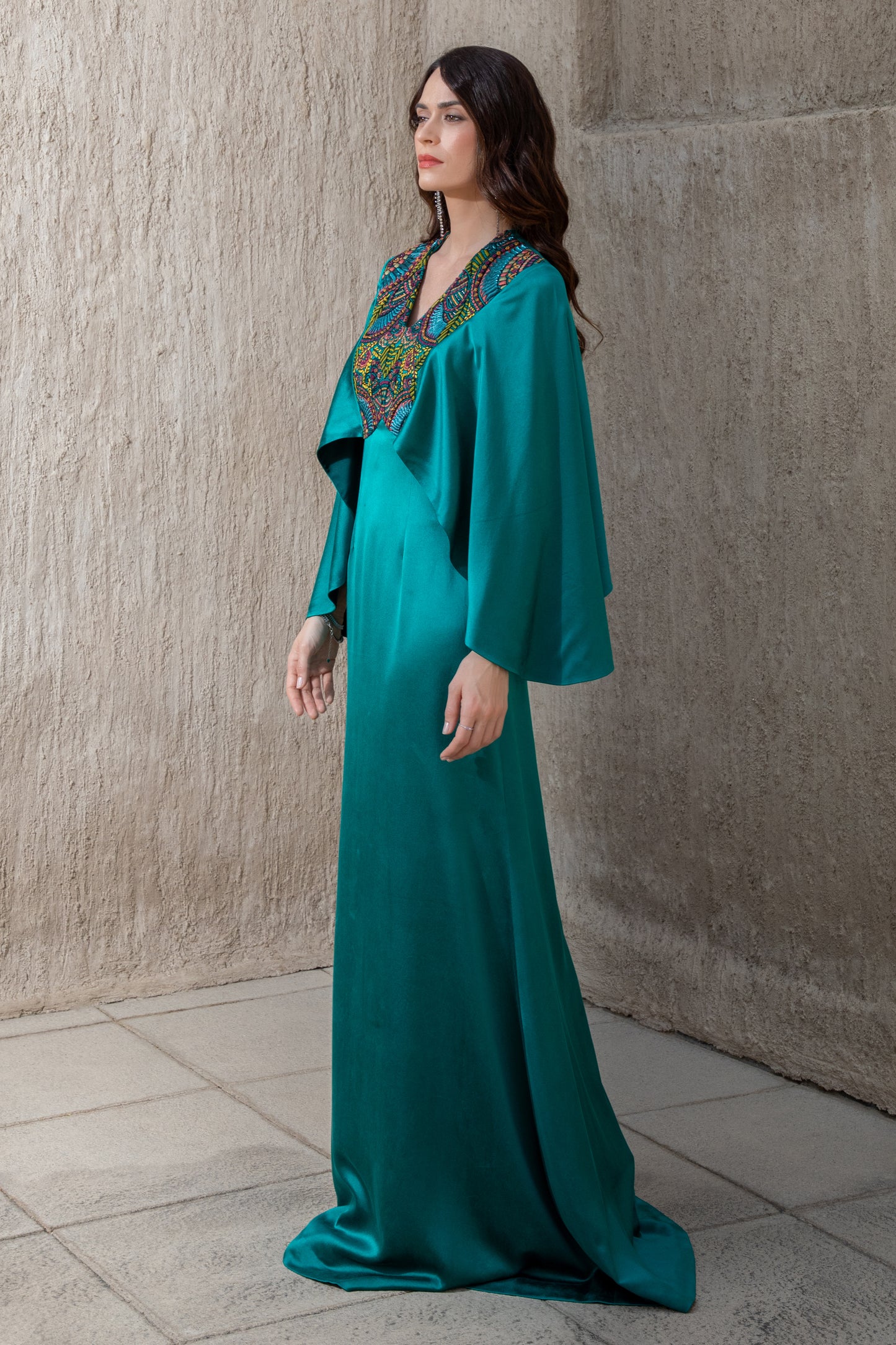Side profile of emerald gown with elegant drape and embroidery detail