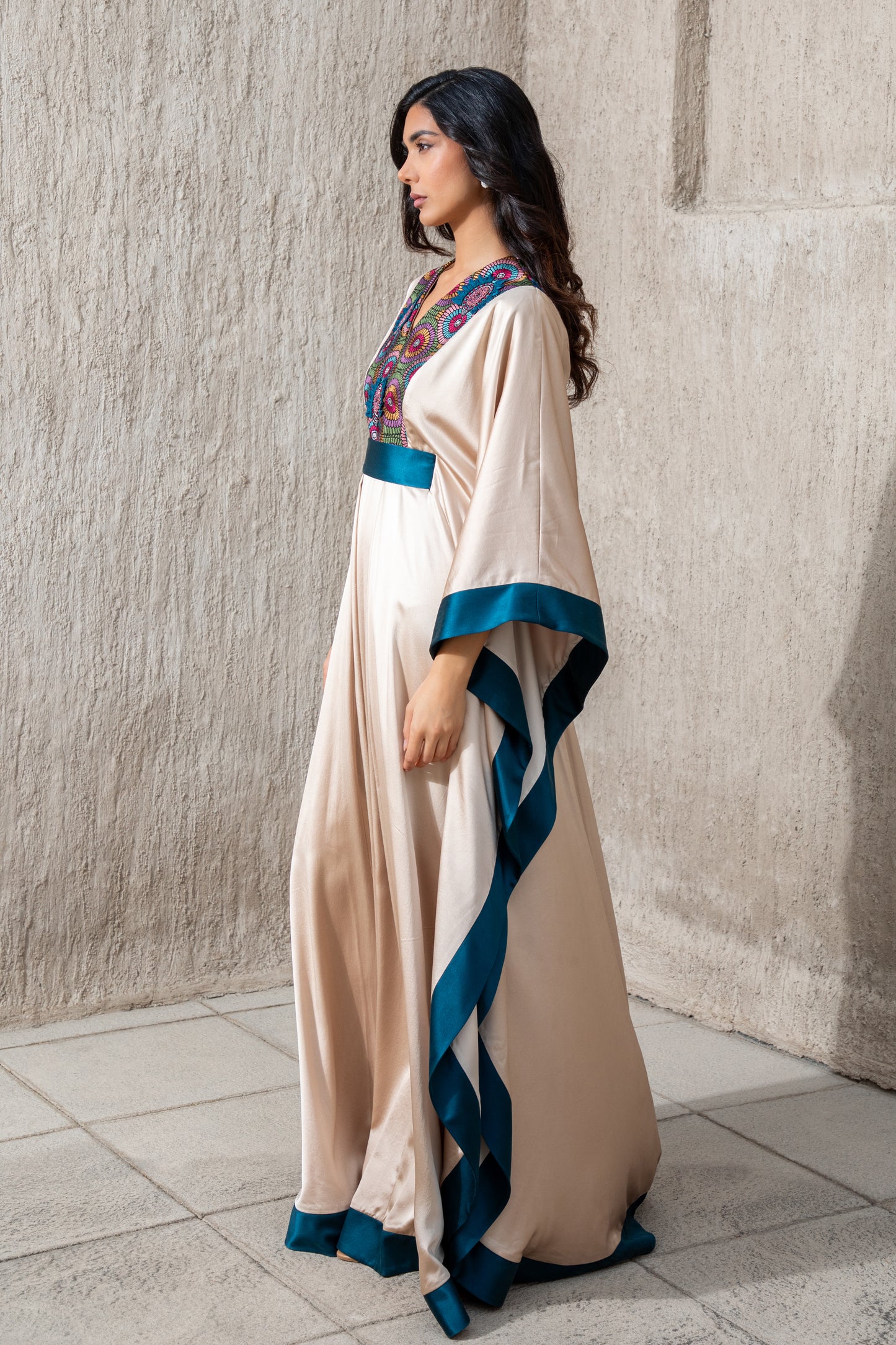 Side view of embroidered vanilla kaftan with teal blue detailing