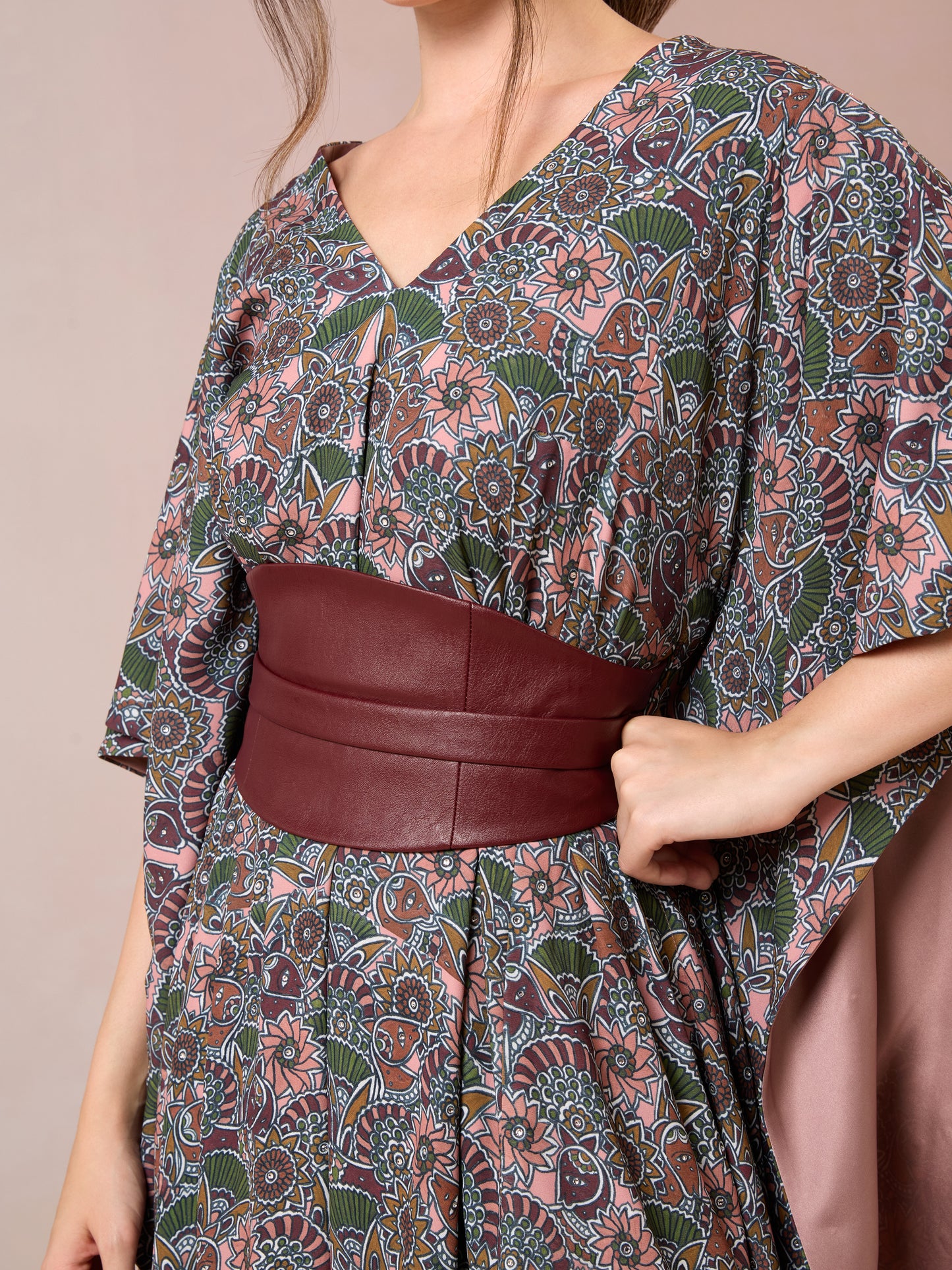 Close-up of floral kaftan fabric and structured maroon waist belt