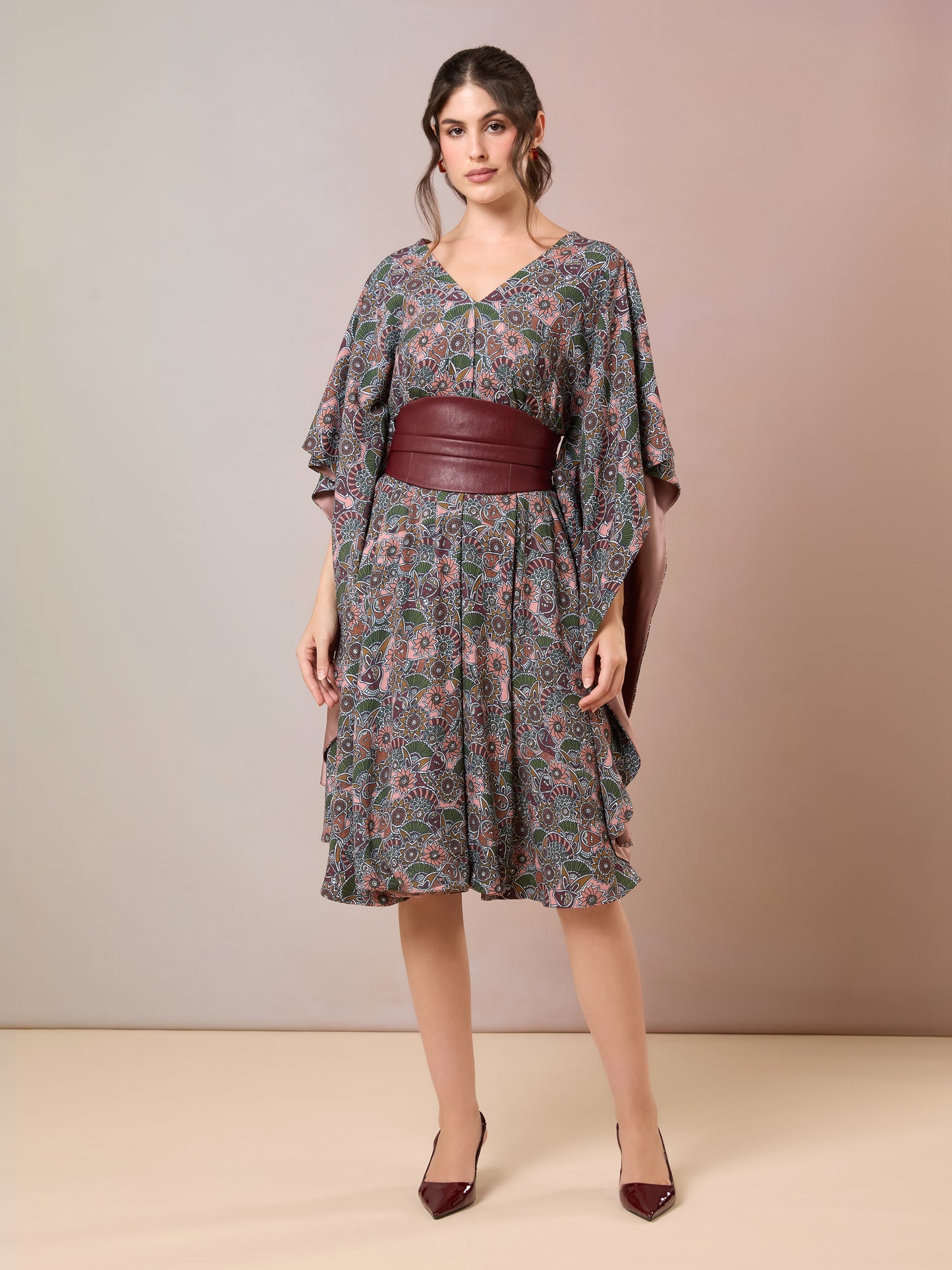 Model in floral knee-length kaftan with flared sleeves and wide maroon waist belt