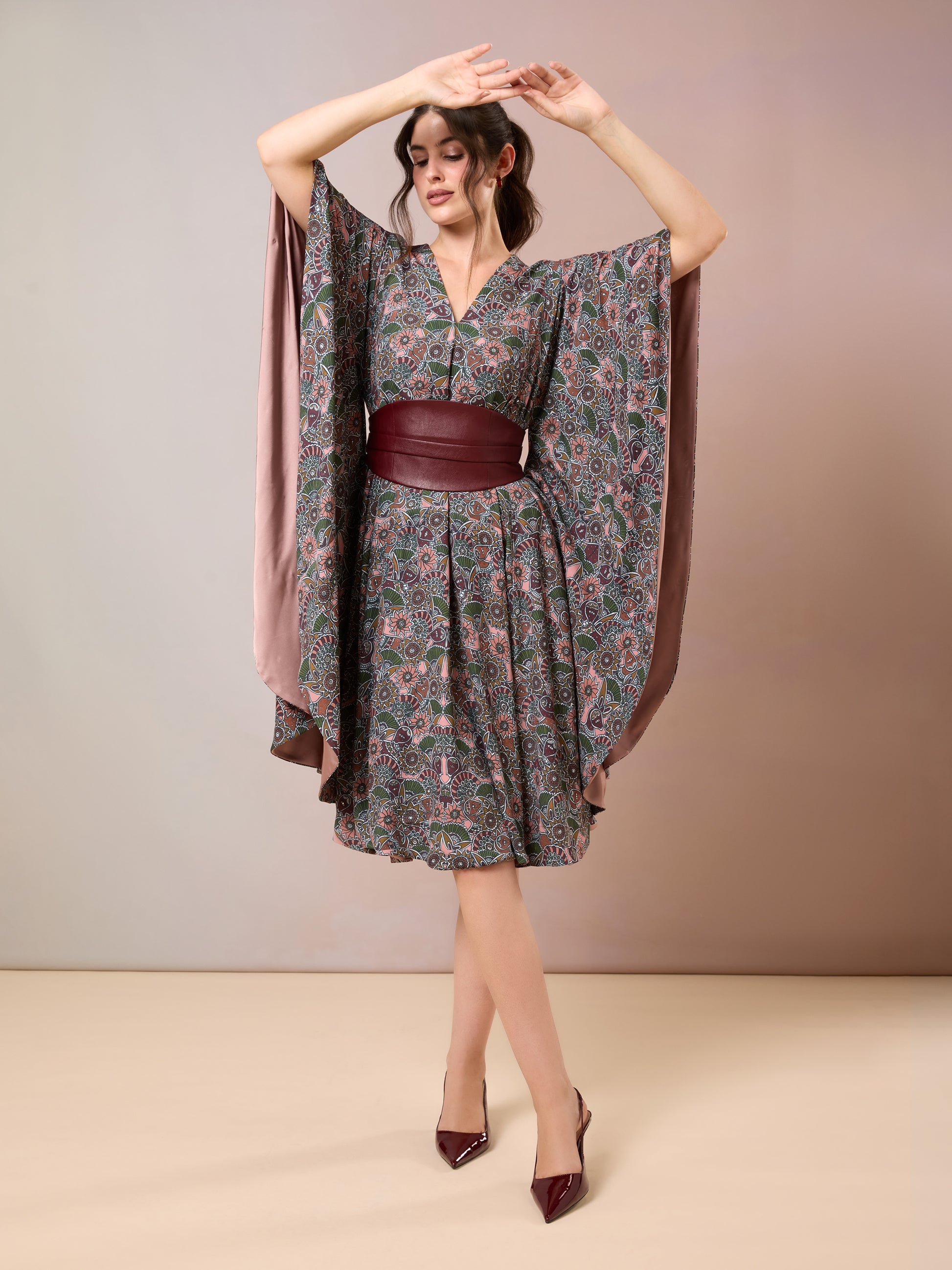 Model twirling in printed V-neck kaftan with flutter sleeves and maroon belt
