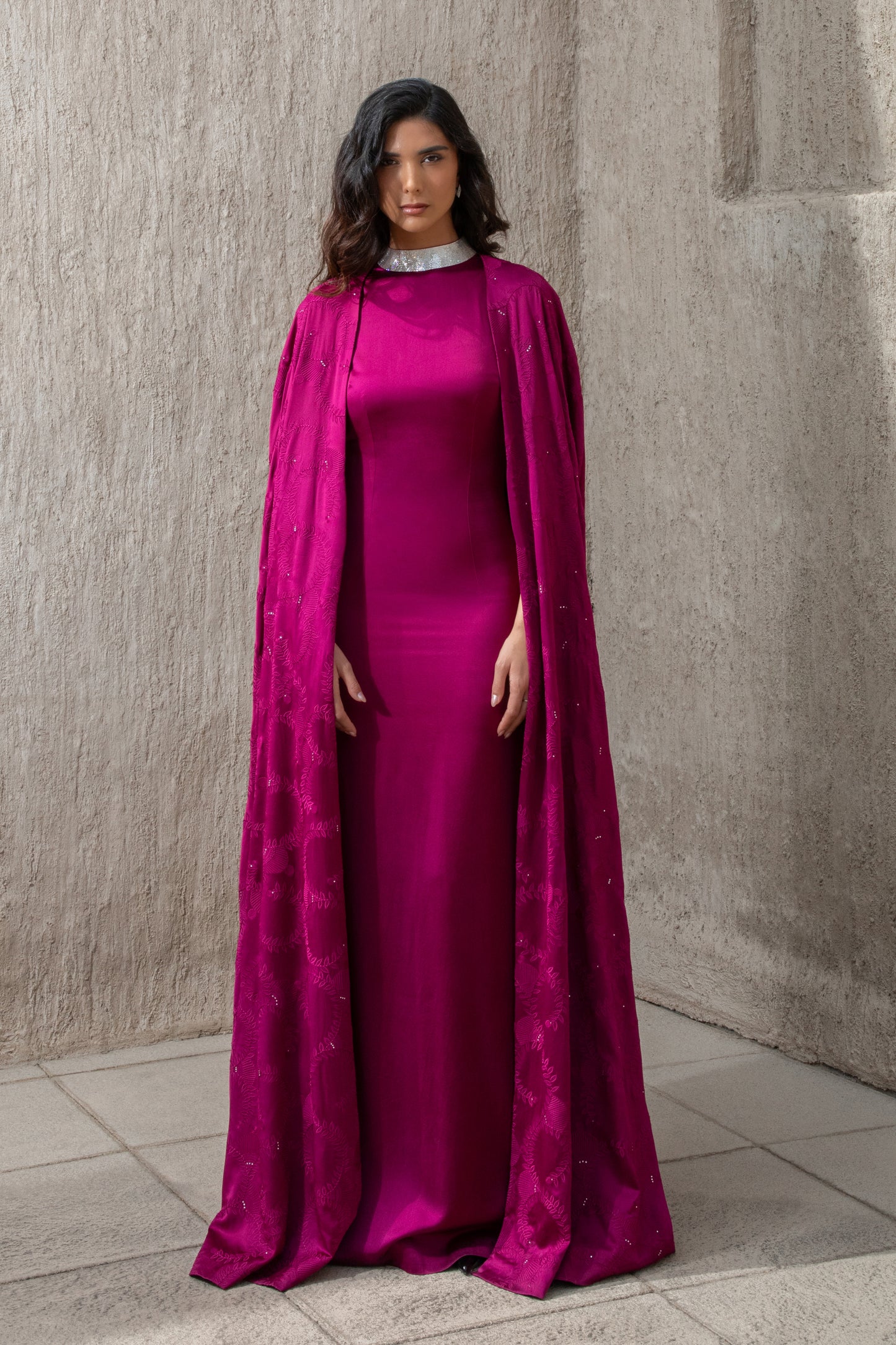 Model wearing cranberry evening gown with embellished cape