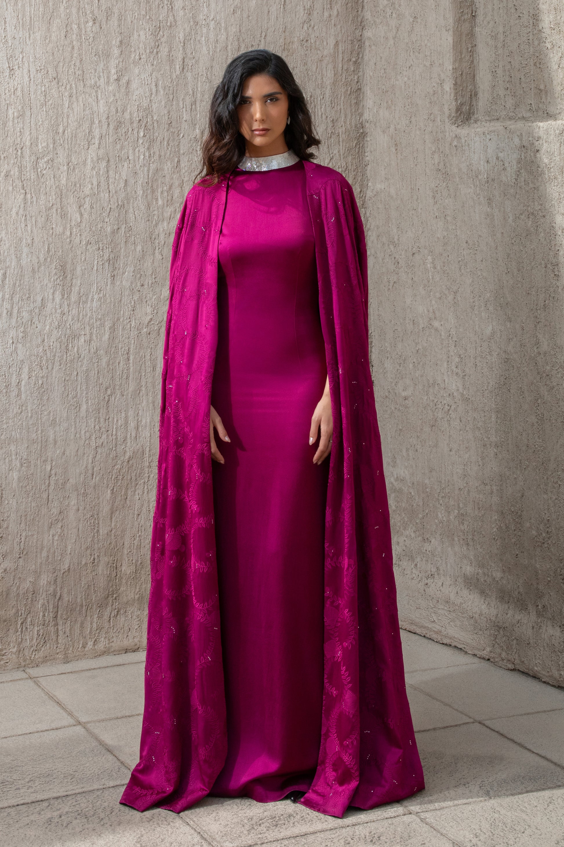 Model wearing cranberry evening gown with embellished cape