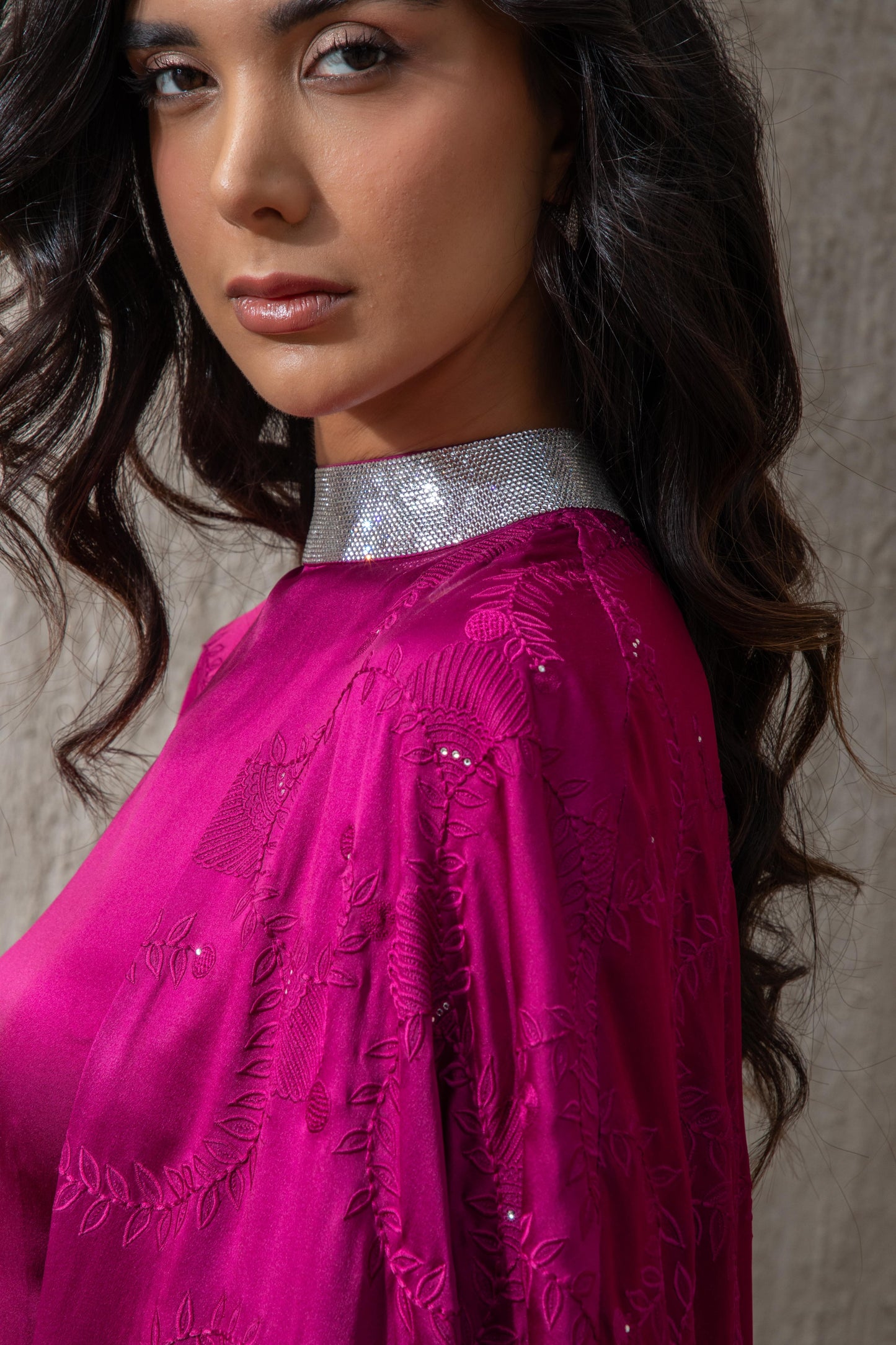 Close-up of embellished neckline on cranberry gown with lace cape