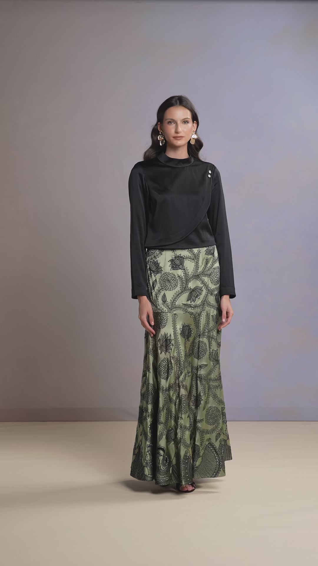 Model walking in Sage Whisper green skirt and black satin top