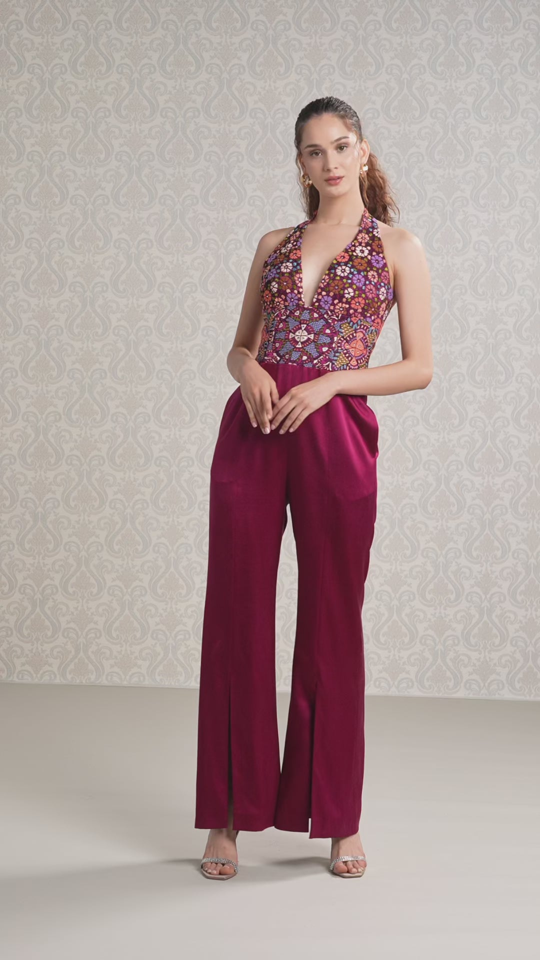 Women walking in cranberry silk satin halter jumpsuit with floral embroidery