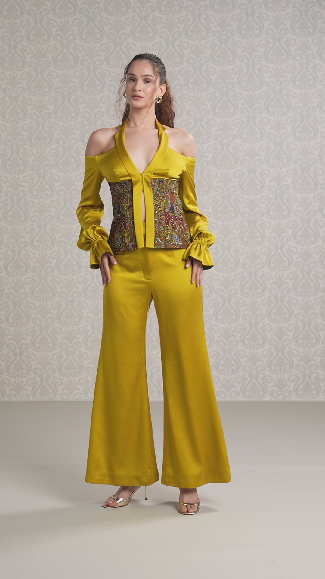 Model walking in harvest gold silk satin top and trouser set with corset detail