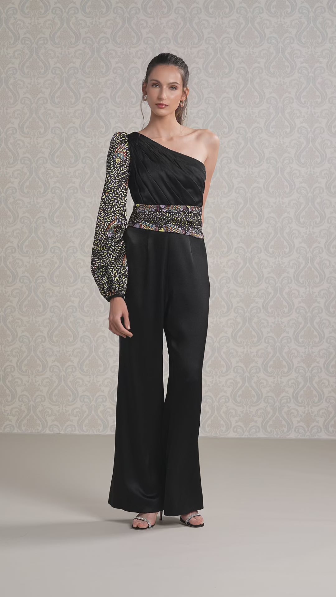 women walking in black ice silk satin one-shoulder jumpsuit with sequined details