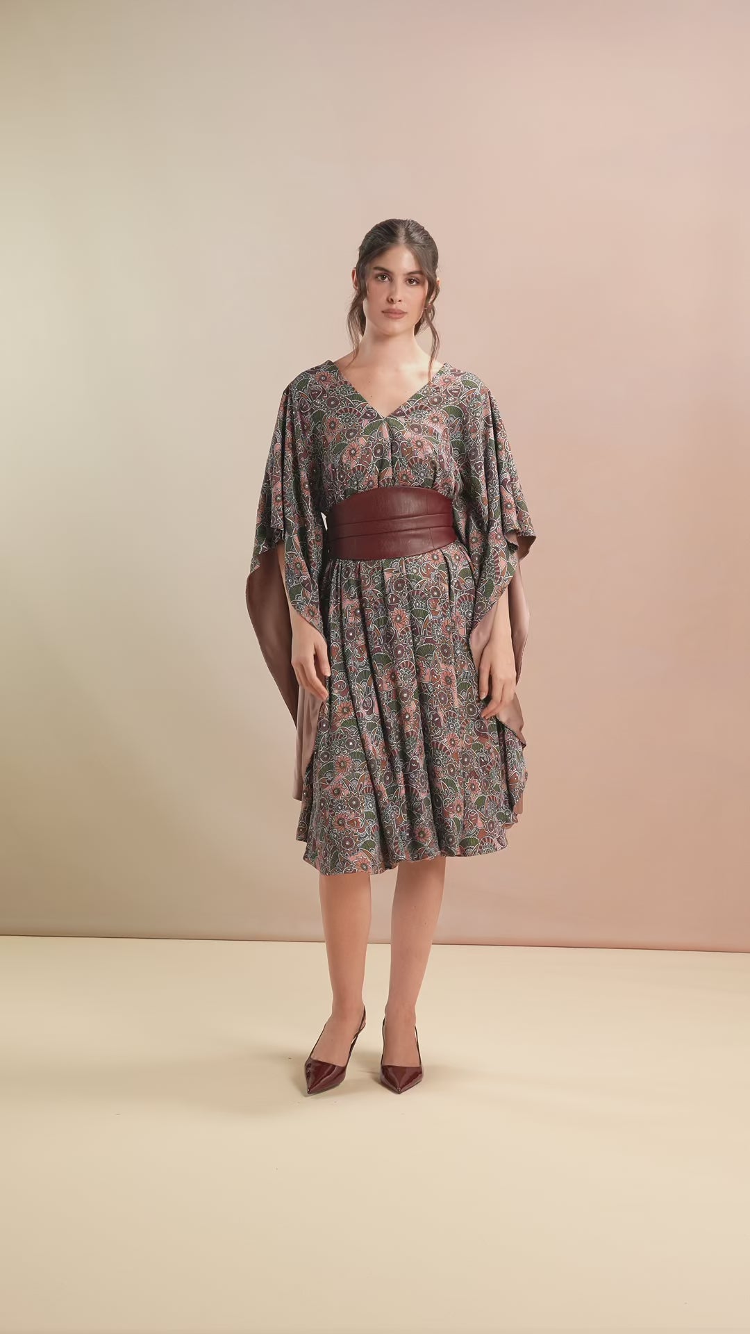 Model walking in floral belted kaftan with flutter sleeves and V-neckline