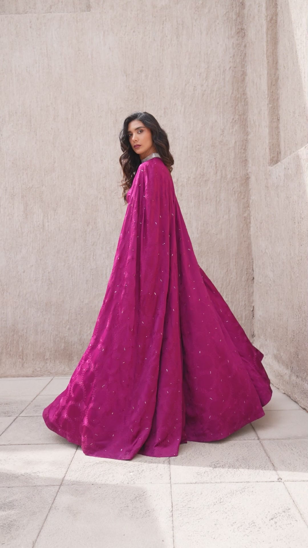 Model walking in full-length cranberry evening gown with cape