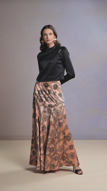 Model walking in Coral Blush printed skirt and black satin draped top