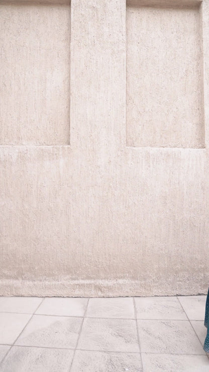 Model walking in vanilla and blue two-piece outfit with flowing skirt