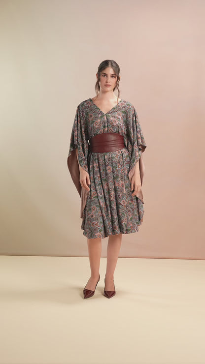 Model walking in floral belted kaftan with flutter sleeves and V-neckline
