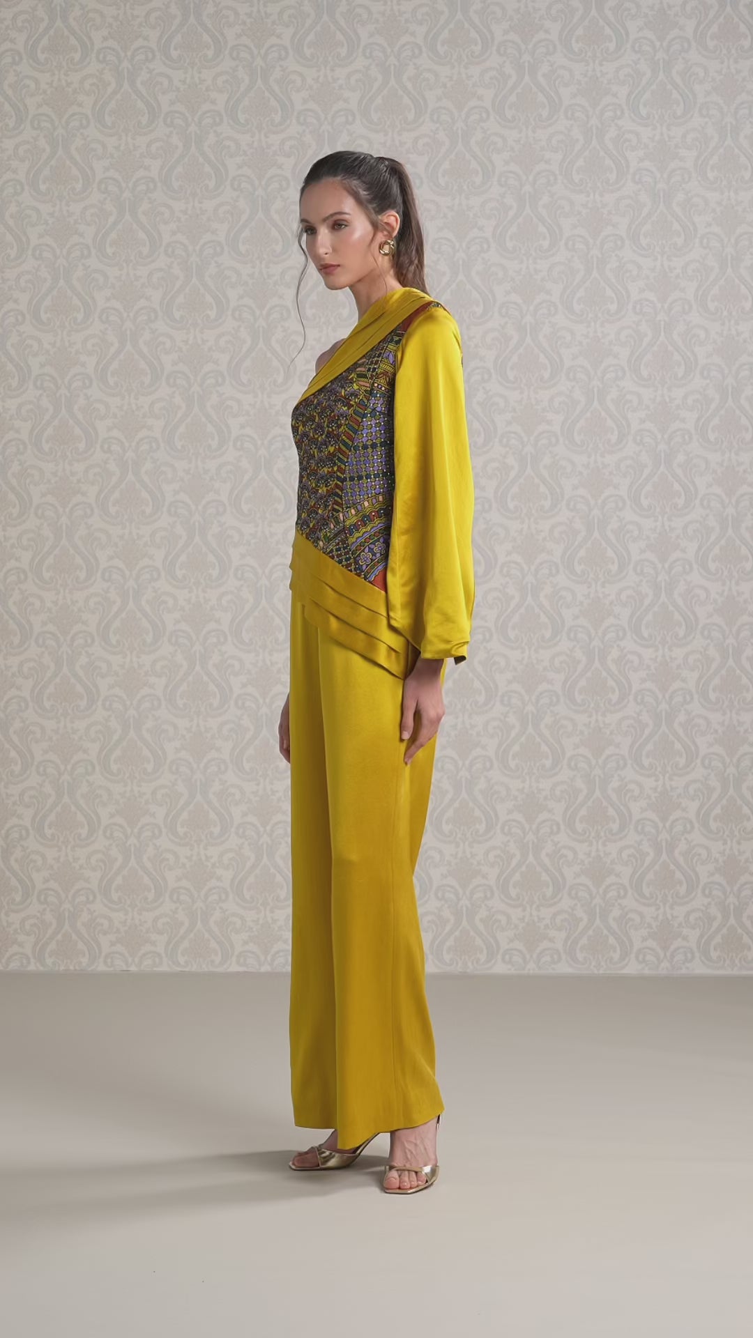 Women walking in harvest gold silk satin jumpsuit with embroidered one-shoulder design