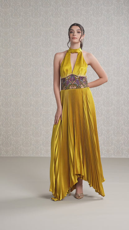Model walking in halter neck Harvest Gold long dress with pleated flow and bold waistband