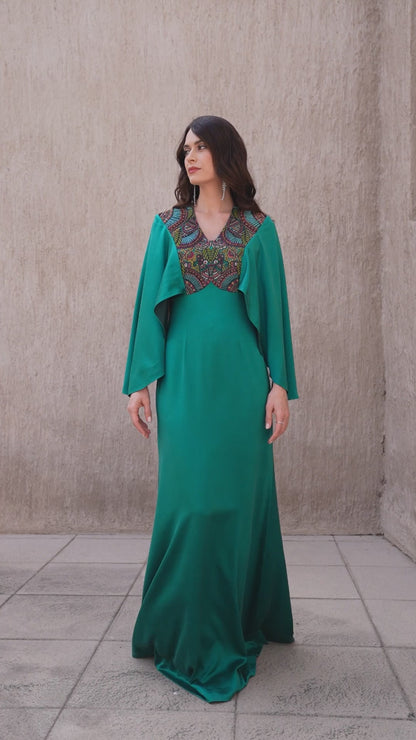 Model walking in emerald gown showcasing embroidered details 